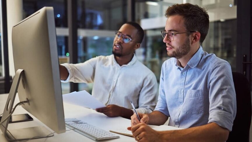 Two people sitting together at a computer, collaborating on a task.