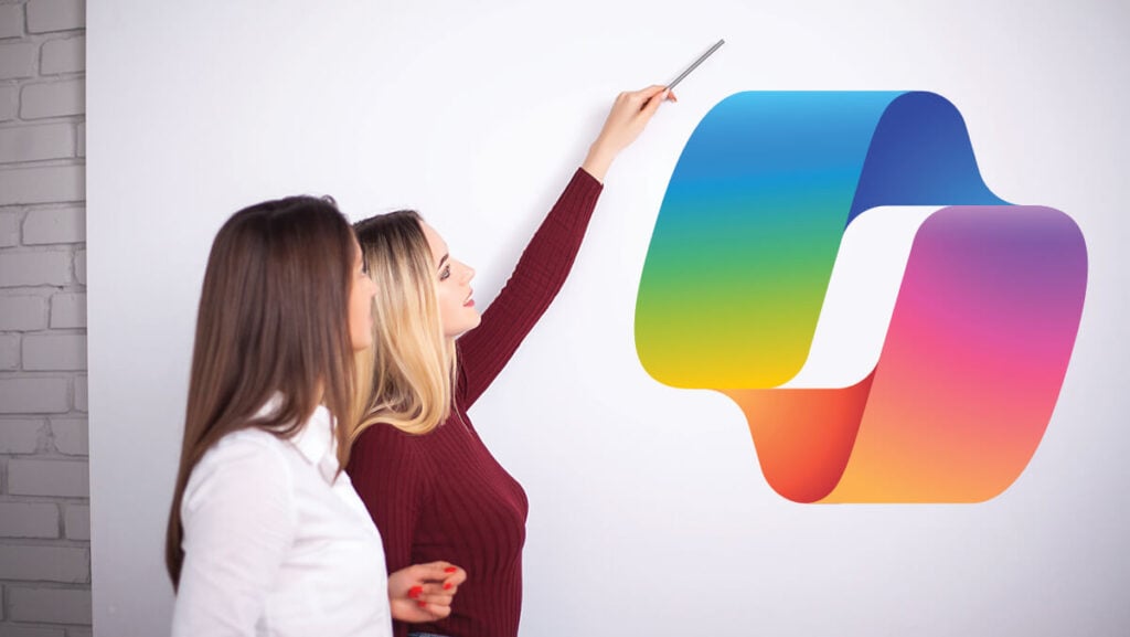 Two business professionals discussing a large colorful Microsoft Copilot logo displayed on a whiteboard during a presentation.