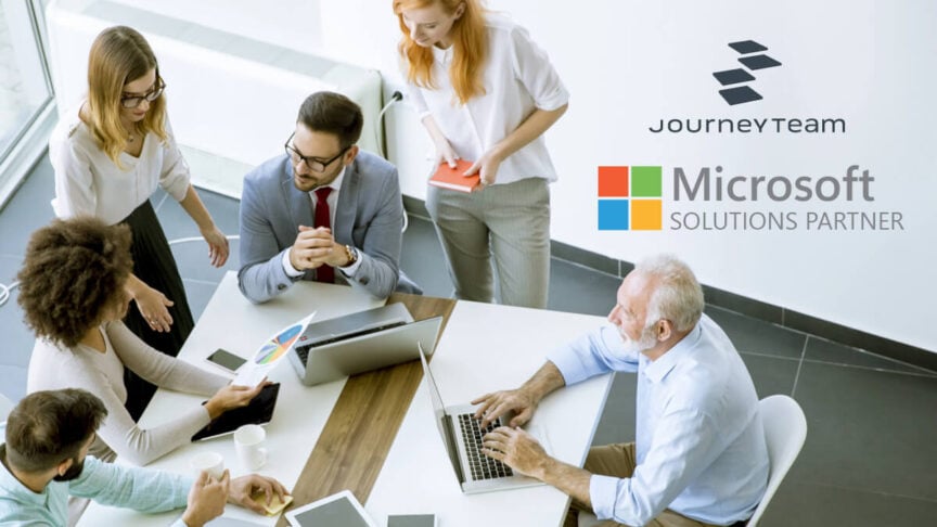 JourneyTeam representatives standing together at a professional event, with a branded display and Microsoft Partner signage in the background, emphasizing collaboration and technology expertise.