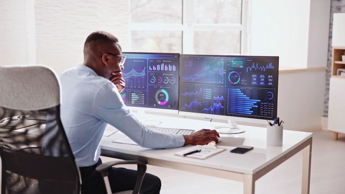 Business professional reviewing digital analytics dashboard with charts and graphs on a large screen.